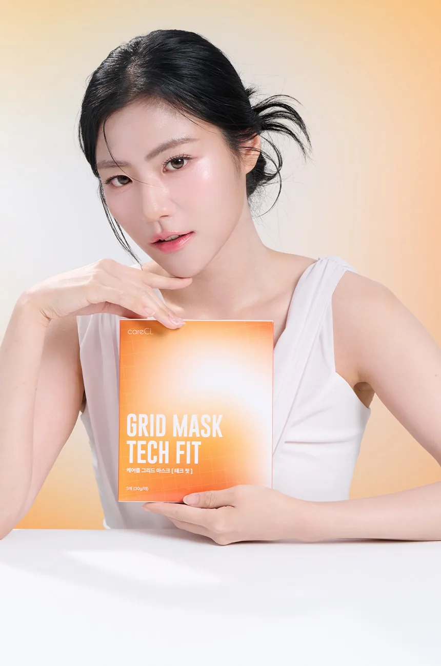 Modelo sosteniendo la caja Grid Mask TECH FIT sobre degradado naranja